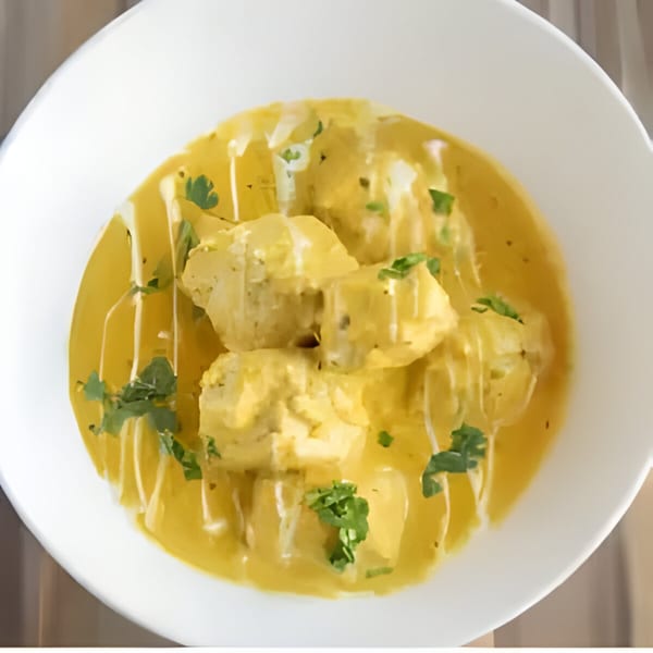 Indian Malai Kofta, vegetable dumplings in a creamy yellow sauce, garnished with fresh cilantro.